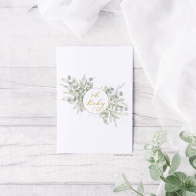 Oh Baby Greeting Card Staged "Oh Baby" greeting card staged on distressed white wood background with eucalyptus leaves and white chiffon at the corner. Artwork features a watercolor floral wreath with "oh baby" in calligraphy
